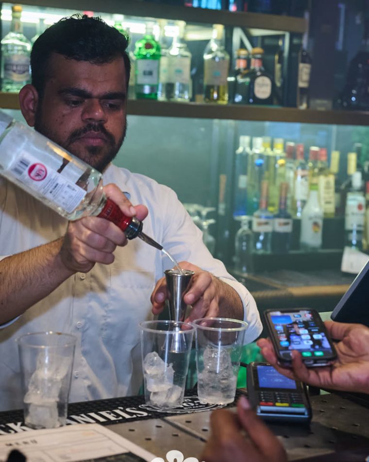 A bartender building a drink behind the fully stocked bar at Cabo in the City.
