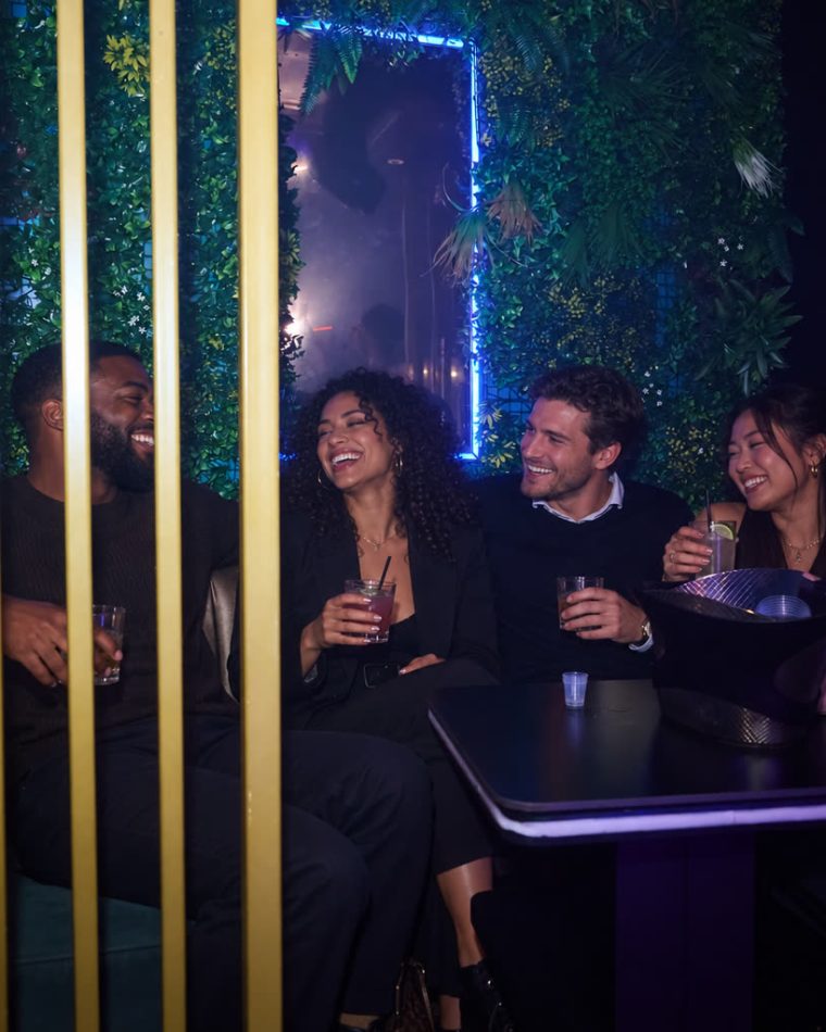 Four people sharing a booth beside the foliage wall at Cabo.