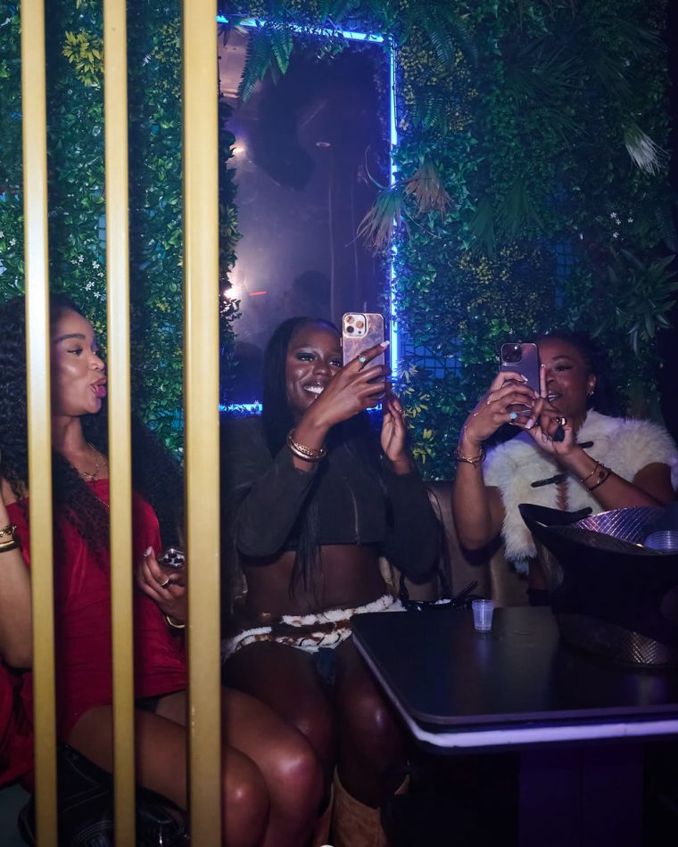 A table of guests in a booth at Cabo beside the foliage wall and gold screen.