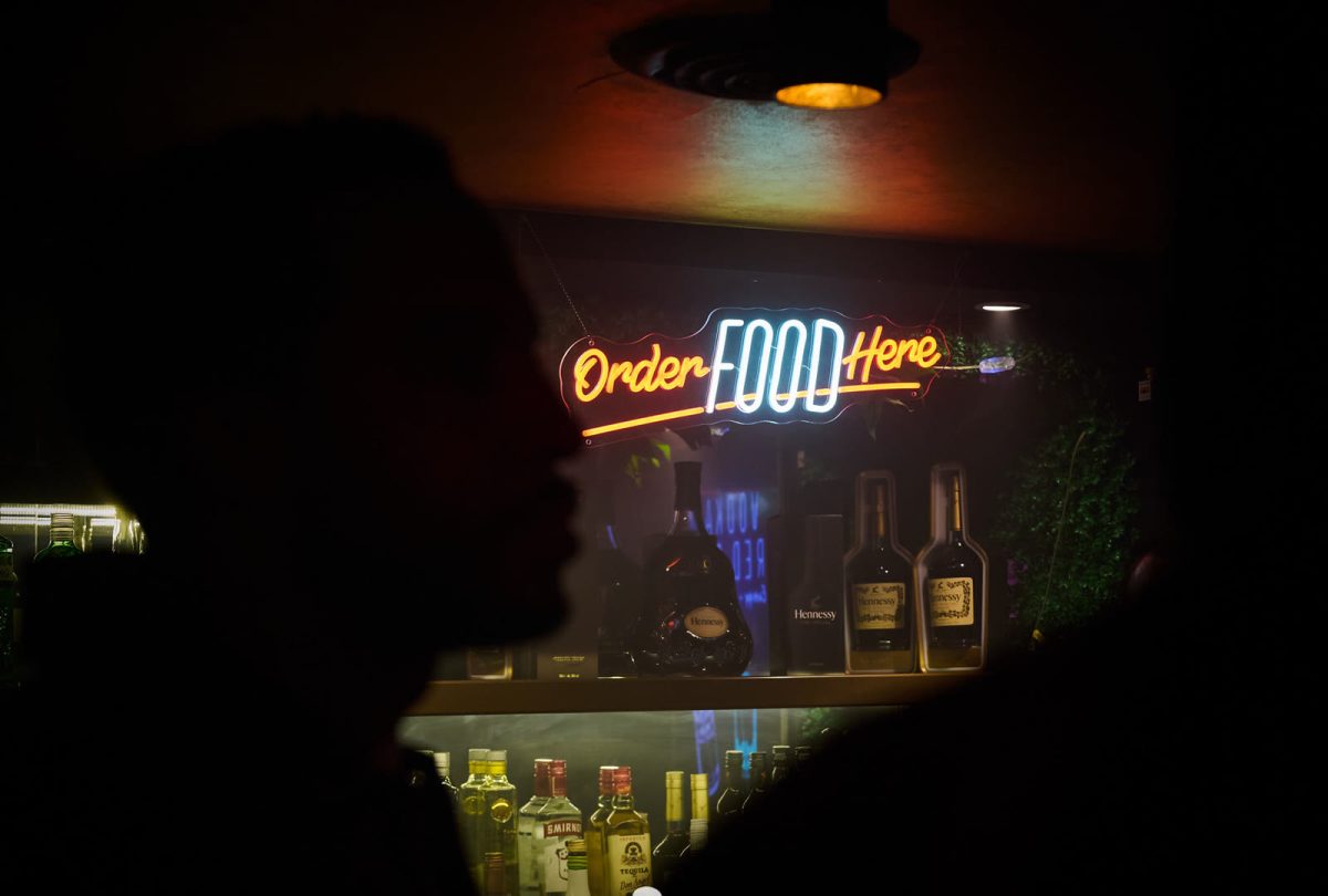 The spirits shelf behind the bar at Cabo, lit warm against the dark room.