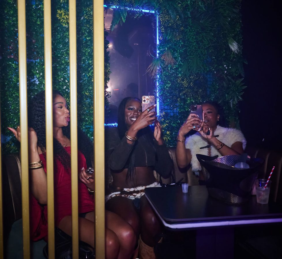 A table of guests in a booth at Cabo beside the foliage wall and gold screen.