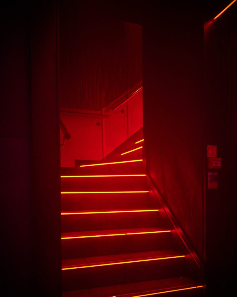 The staircase down into Cabo, each step edged in red light.